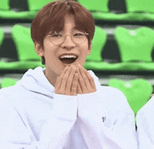 a young man wearing glasses and a white hoodie is laughing .