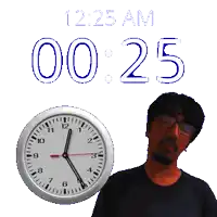 a man standing next to a clock that says 12:25 am on it