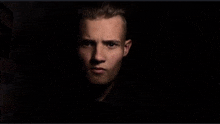 a close up of a man 's face in the dark looking at the camera .