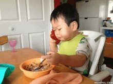 a little boy is eating cereal and talking on a cell phone