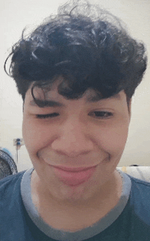 a young man with curly hair is smiling and making a face