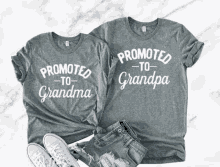 a couple of t-shirts that say promoted to grandma and grandpa .