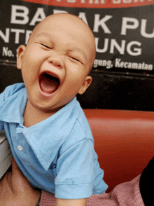 a baby is laughing in front of a sign that says ' barakpu '