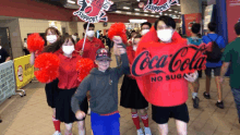 a man in a coca cola no sugar costume is surrounded by people