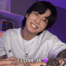 a young man with a tattoo on his arm is smiling and says i love jk