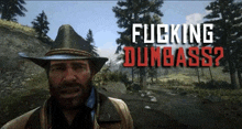 a man in a cowboy hat stands in front of a sign that says " fucking dumbass "