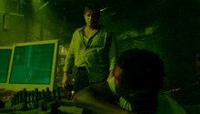 a man in a green shirt stands next to a man laying on the floor
