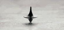 a black spinning top is sitting on top of a white surface .