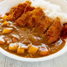 a bowl of chicken curry with rice on a wooden table .