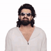 a man with a beard and sunglasses is wearing a white shirt .