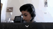 a young boy wearing headphones is on a video call with yunus emra a