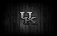 the kentucky basketball logo is on a wooden background .