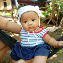 a baby wearing a striped shirt and a white hat