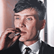 a man in a suit is smoking a cigarette in his mouth .