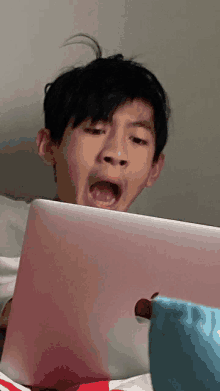 a young boy is yawning while looking at a laptop