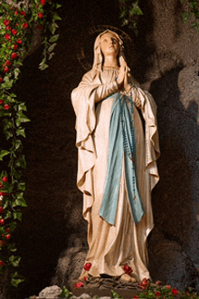 a statue of the virgin mary is surrounded by flowers and leaves