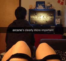 a man and a woman watching arcane on a television