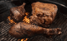 several pieces of meat are cooking on a grill with flames