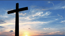 a cross against a sunset sky with clouds