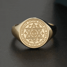 a gold ring with an all seeing eye in the center and a circle around it that says ' ihaild '