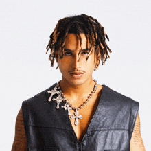 a man with dreadlocks is wearing a leather vest