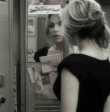 a woman is looking at her reflection in a mirror with a sign that says " satisfaction "