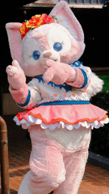 a stuffed animal wearing a pink and white outfit with flowers on her head