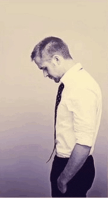 a man in a white shirt and black tie looks down