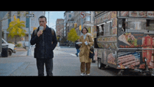 a man drinking from a cup next to a food truck that says ' the master of culinary ' on it