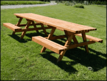 a wooden picnic table sits in a grassy field