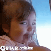 a little girl with a pacifier in her mouth and a star tamil chat logo