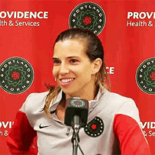 a woman is smiling in front of a microphone in front of a red background that says portland health and services .