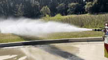 a fire truck spraying water on a sidewalk with trees in the background