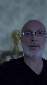 a bald man wearing glasses looks at the camera