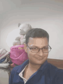 a man wearing glasses is smiling in front of a teddy bear and a pink basket