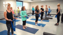 a group of women are standing on yoga mats in a room with a be st logo on the wall