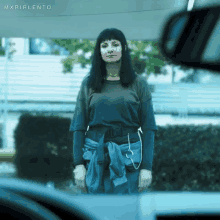 a woman standing in front of a car with the word mxrirlento on the bottom right