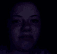 a woman 's face is visible in the dark with a purple background