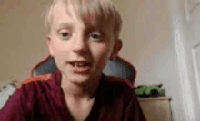 a young boy is looking at the camera while sitting in a chair in a room .