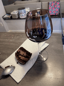 a glass of wine sits on a napkin next to a slice of cake