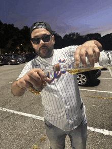 a man wearing a new york mets jersey is pouring a drink