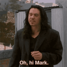 a man with long hair and a black jacket says oh hi mark