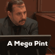 a man in a suit stands in front of a computer monitor that says a mega pint