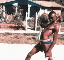 a man in a bikini is dancing on the sidewalk in front of a house .