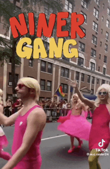 a group of drag queens are walking down a street with the words niner gang written above them