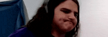 a woman with long hair is wearing headphones and making a face .