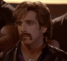 a man with a mustache and a necklace is wearing a leather jacket