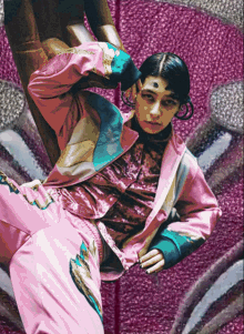 a woman in a pink jacket and pants is laying on a purple surface