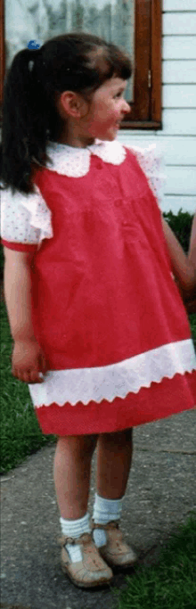 a little girl is wearing a red dress with white polka dots