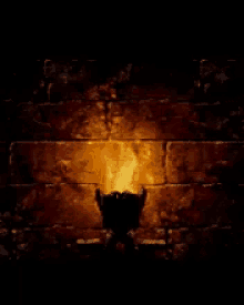 a silhouette of a person standing in front of a brick wall with a flame coming out of it